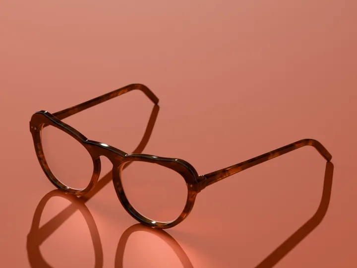 Alba cat-eye glasses in Amber tortoise, in low sun on a warm ground