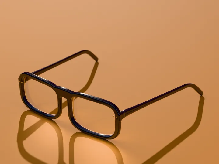 Bram rectangle glasses in Deep navy, in low sun on a warm ground