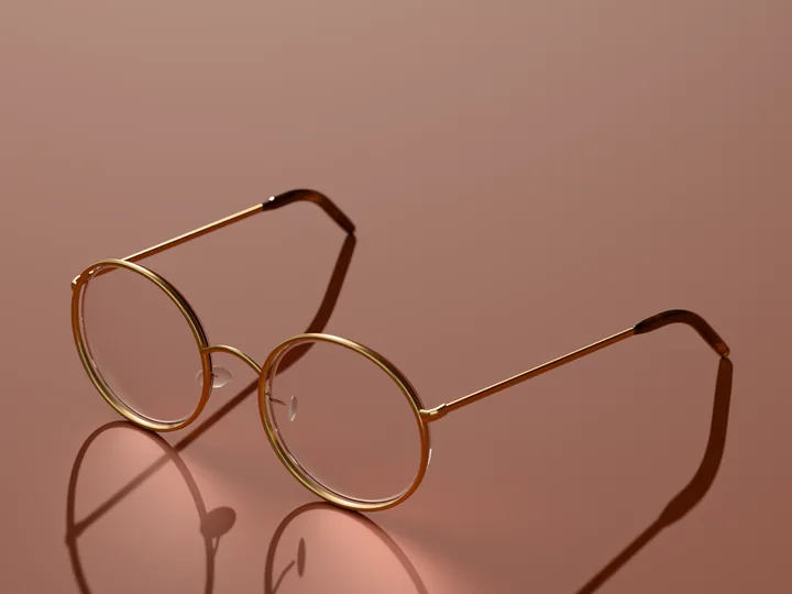 Rowan round glasses in Brushed gold, in low sun on a warm ground